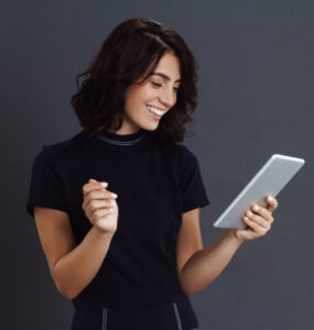 beautiful young woman posing grey wall holding tablet hands
