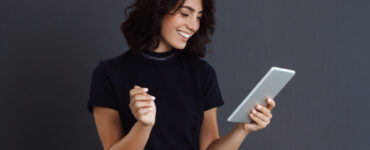 beautiful young woman posing grey wall holding tablet hands