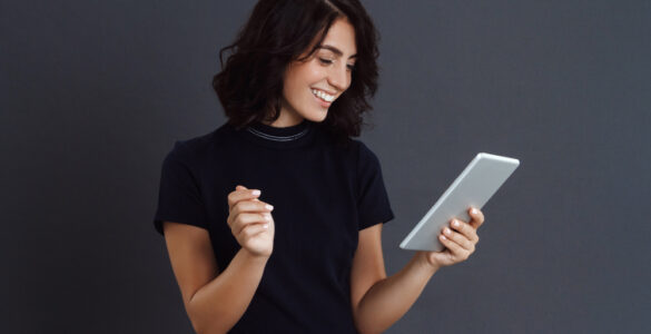 beautiful young woman posing grey wall holding tablet hands