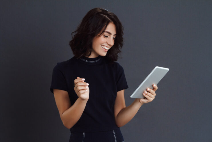 beautiful young woman posing grey wall holding tablet hands