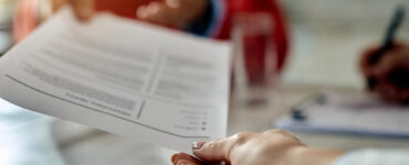 closeup job applicant giving his resume during job interview office