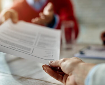 closeup job applicant giving his resume during job interview office