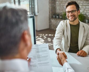 happy male candidate greeting member human resource team job interview office