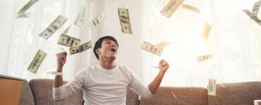 happy man with cash dollars flying home office rich from business online concept