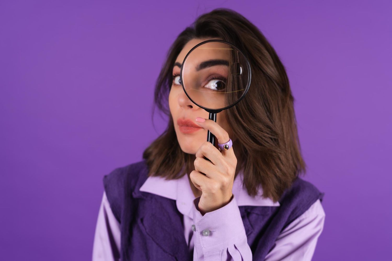 young woman shirt vest purple background having fun with magnifying glass hand